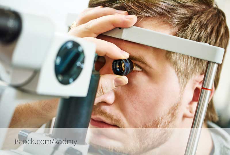 Mann schaut bei einer augenärztlichen Untersuchung durch ein Kontrollgerät.