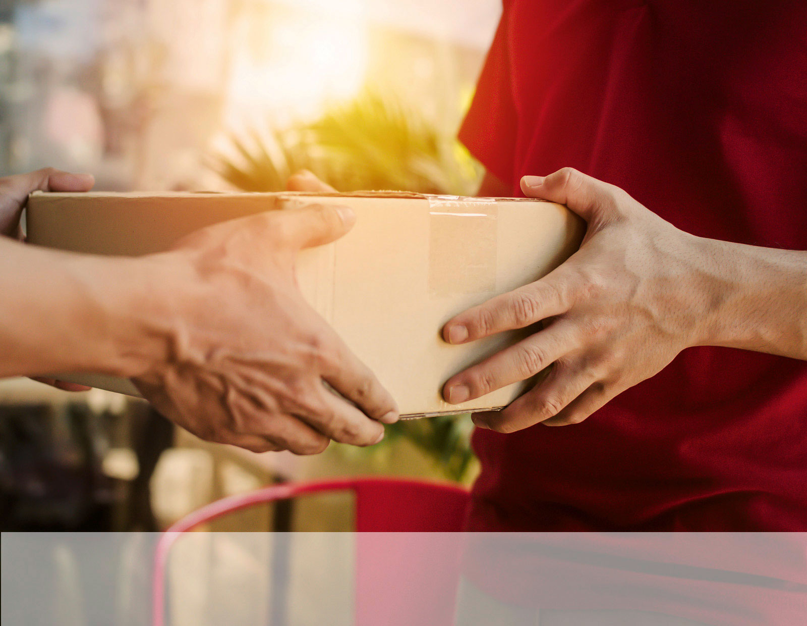 Ein Paketzusteller übergibt ein Paket  an den Empfänger.