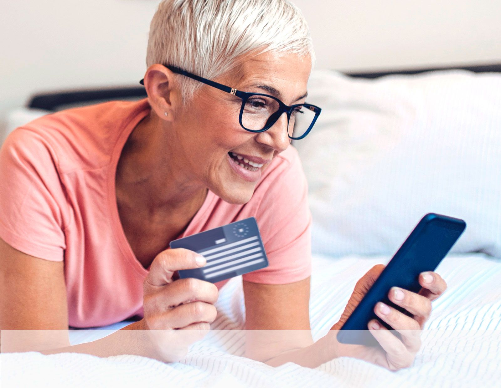 Eine Frau liegt auf dem Bett, hält Ihre Versichertenkarte und ihr Smartphone in der Hand.